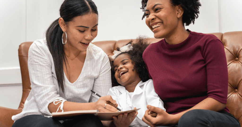 two moms and daughter laughing and looking at list