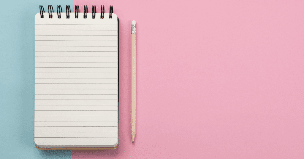 pencil and small flip notebook on blue and pink background